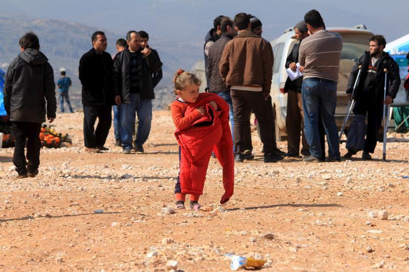 An internally displaced Syrian girl who fled from Aleppo carries a red jacket in the village of Batabo, Syria on February 14, 2016. 