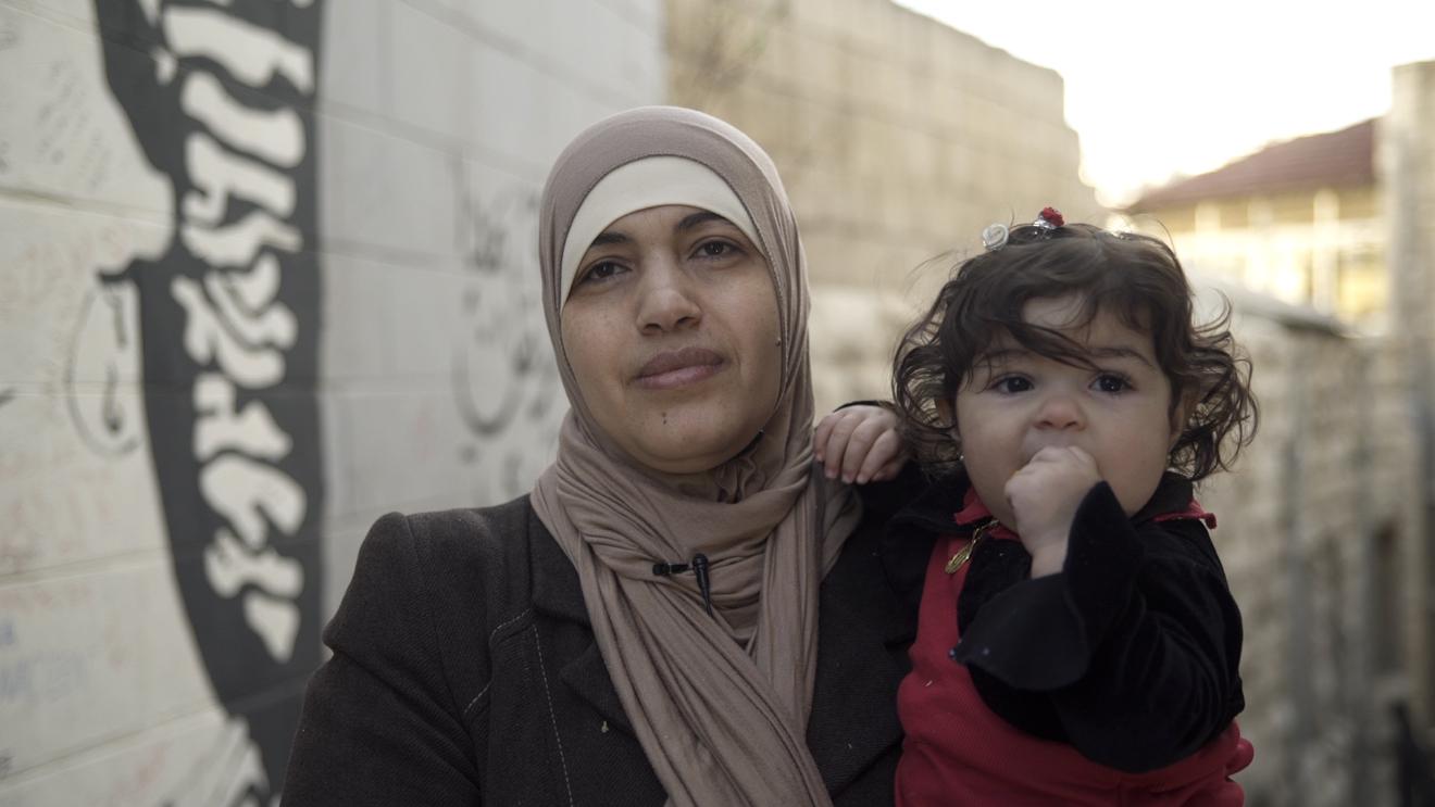 A Jordanian woman married to a foreign national carrying her daughter, one of her four children without Jordanian citizenship, on February 9, 2018 in Amman, Jordan.