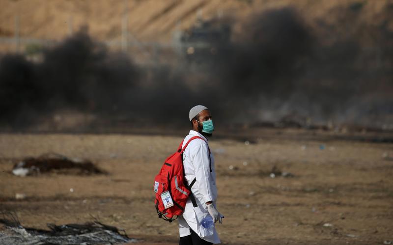 Un secouriste palestinien dans le sud de la Bande de Gaza, devant des nuages de fumée noire près la barrière de séparation avec Israël, lors d'une manifestation de résidents de Gaza tenue le 18 mai 2018.