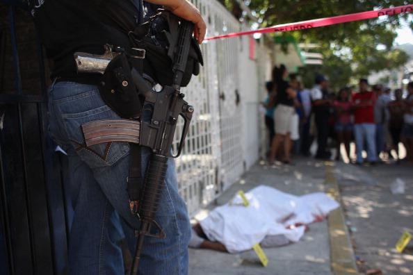 Un policía observa un cadaver cubierto