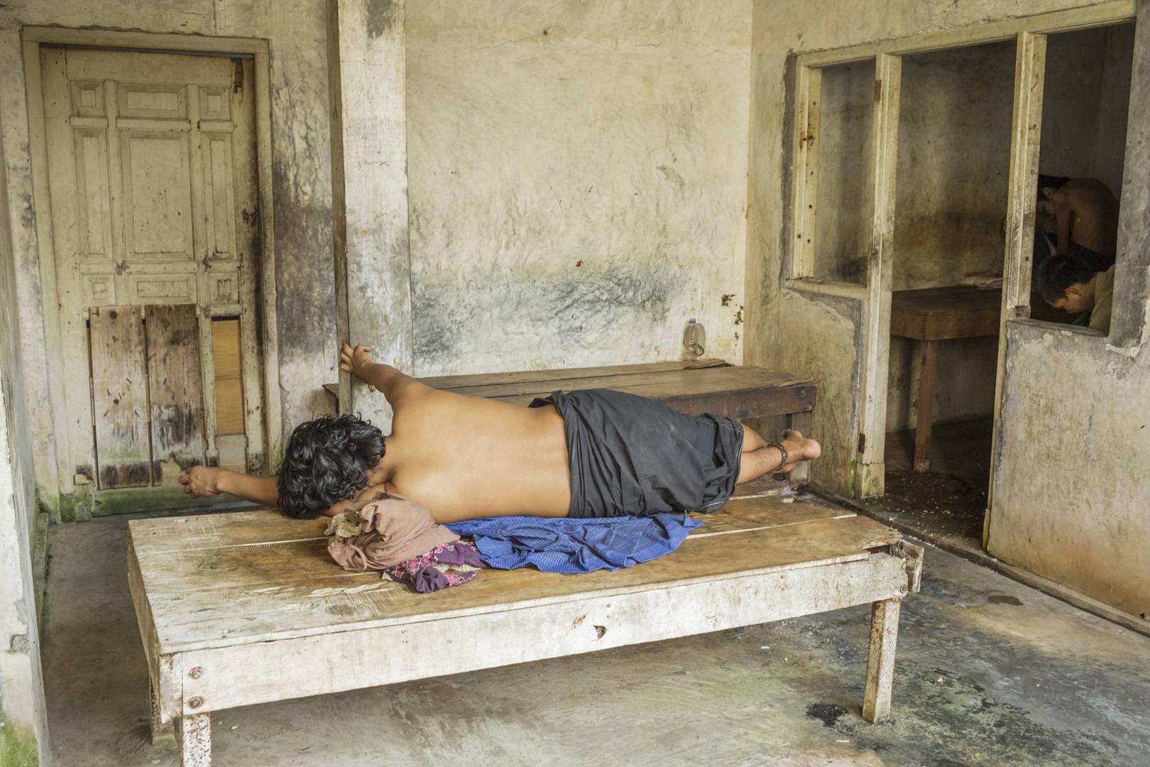 Seorang laki-laki yang diduga atau didiagnosis memiliki disabilitas psikososial terbaring dengan pergelangan kakinya dirantai ke dipan di panti