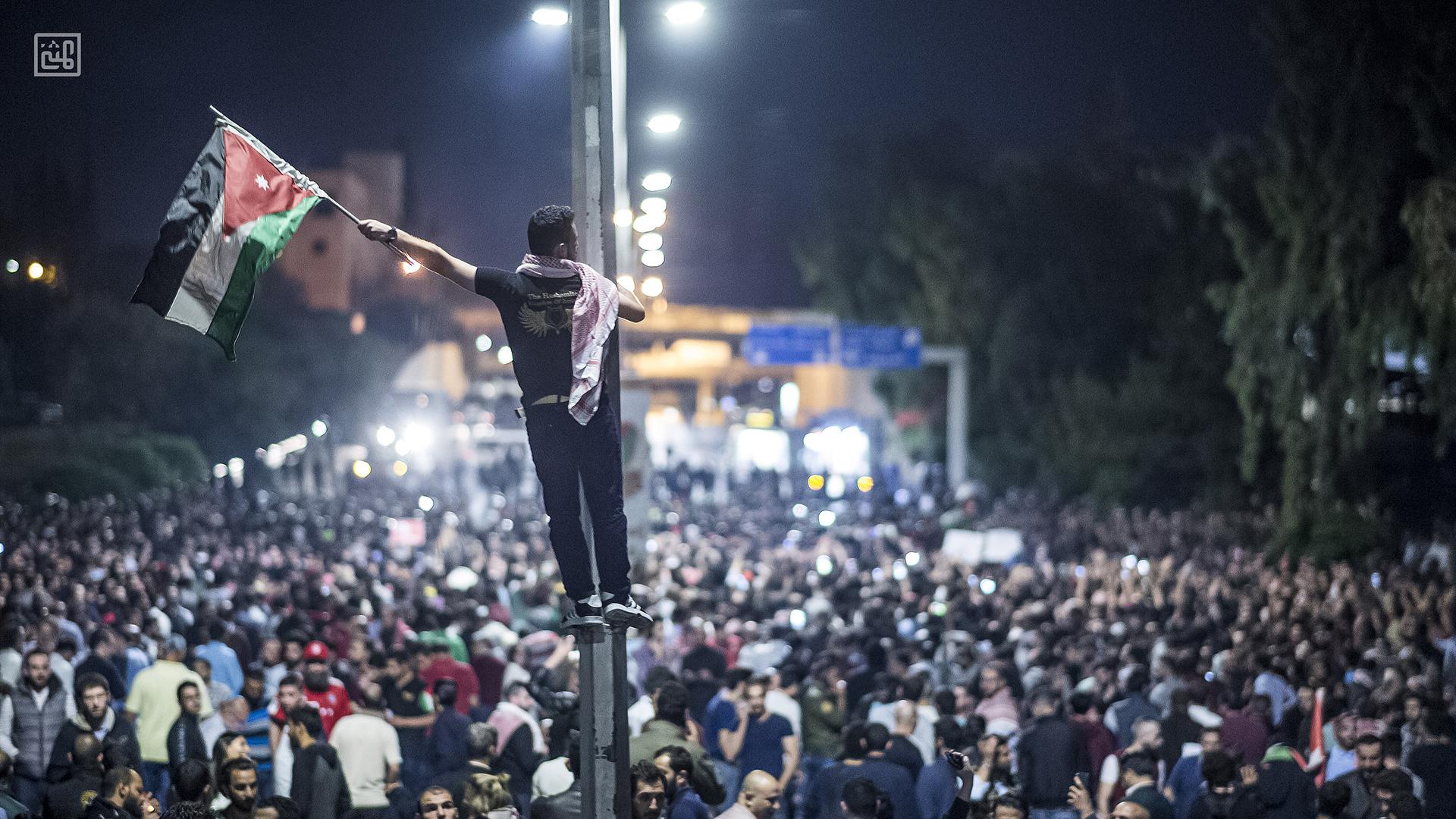 Un homme brandit un drapeau jordanien lors d’une manifestation massive contre les hausses de prix et d’impôts, près du bâtiment où est situé le bureau du Premier ministre à Amman, en Jordanie, en juin 2018.