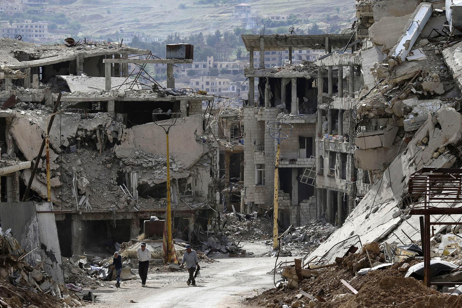Deux hommes et un garçon marchent parmi les décombres d’immeubles bombardés dans la ville de Zabadani, située près de Damas, en Syrie, le 18 mai 2017.