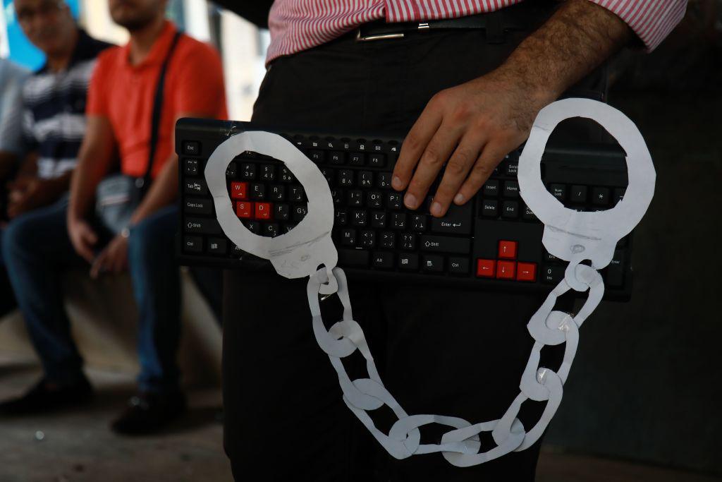 ناشط يحمل لوحة مفاتيح وأصفاد من ورق في وسط بيروت في 24 يوليو/تموز 2018 خلال احتجاج على موجة حديثة من الملاحقات بسبب التعبير السلمي.