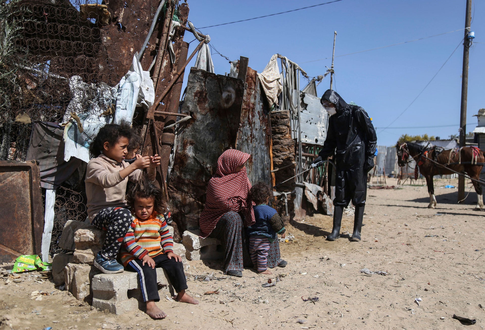 عمال فلسطينيون يرشّون معقمات في مخيّم نهر البارد للوقاية من انتشار فيروس كورونا، في خان يونس، جنوب قطاع غزة، فلسطين، 29 مارس/آذار 2020. 