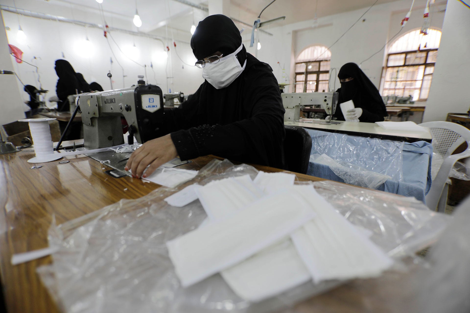 امرأة يمنية تعمل في تصنيع كمامات واقية للوجه في مصنع للنسيج في صنعاء، اليمن، في 17 مارس/آذار 2020. 