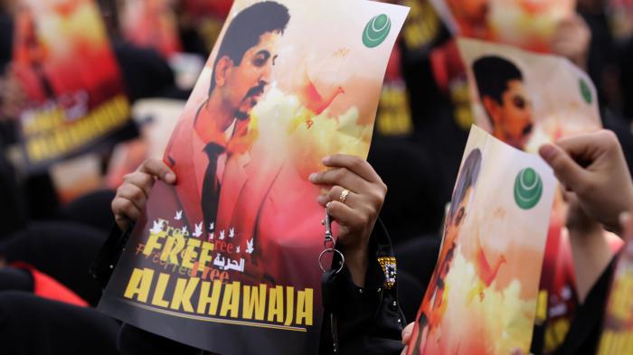 Bahraini anti-government protesters raise signs with images of jailed human rights activist Abdulhadi al-Khawaja Friday, April 6, 2012, in Jidhafs, Bahrain.