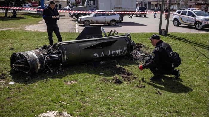 Ukrainian authorities inspect the rocket motor and guidance section of a Tochka-U missile next to the main building of the Kramatorsk train station in eastern Ukraine on April 8, 2022. The phrase “Payback for the children” is painted in Russian on the missile. 
