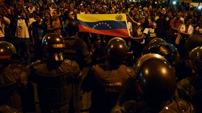 Anti-government students show a national flag to a National Guard barricade during a protest in Caracas, Venezuela, on February 16, 2014. 