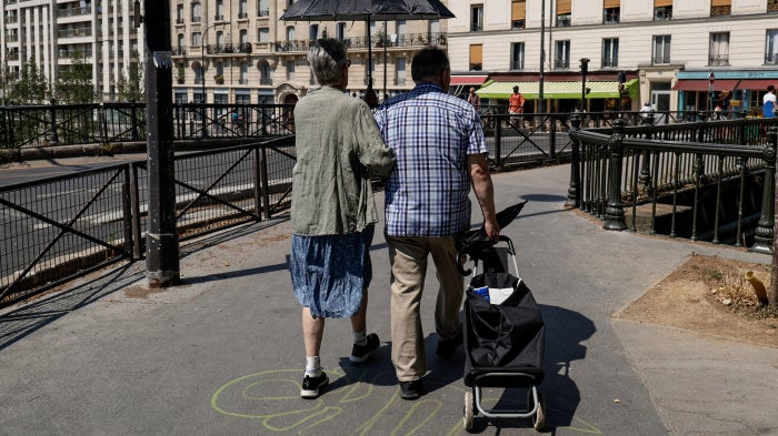 An older couple shelters from the sun under an umbrella near the Canal Saint-Martin in Paris, Ile-de-France, France, on June 26, 2026. 