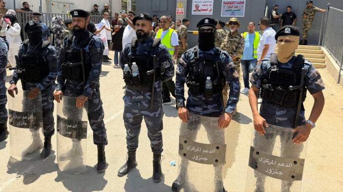 Security personnel stand guard as protesters gather outside the headquarters of the United Nations High Commissioner for Refugees (UNHCR), demanding the organization leave the country and calling for an end to migrant settlement and the deportation of migrants and refugees, in Tripoli, Libya, June 4, 2026. Picture taken with a mobile phone. 