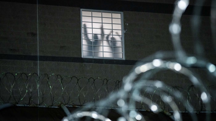 Detainees stand by a window inside the federal immigration center at Delaney Hall