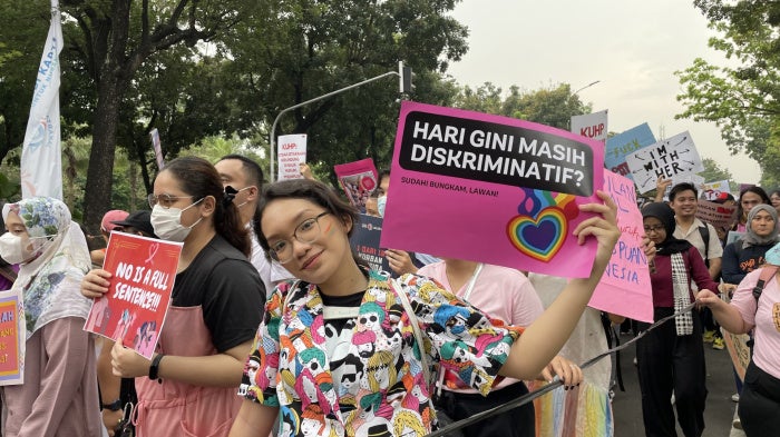 A young protester raises a poster, “Today still discriminatory?” with the love rainbow sign during the Women’s March rally in March 2023 in Jakarta, Indonesia. 