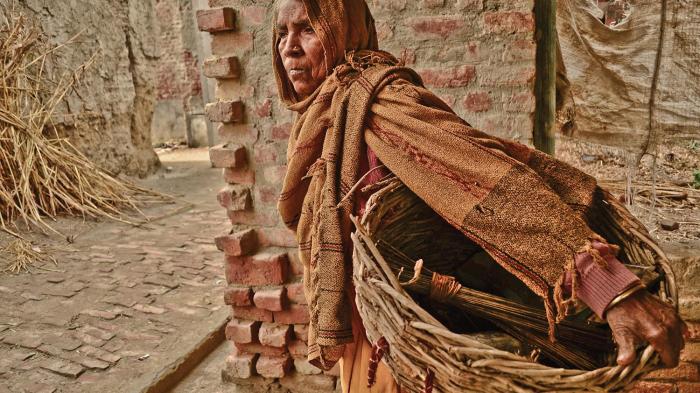  Gangashree walks through the village to manually clean human excrement from dry toilets in Kasela, Uttar Pradesh, which she will collect in her basket and carry to the outskirts of the village for disposal. 