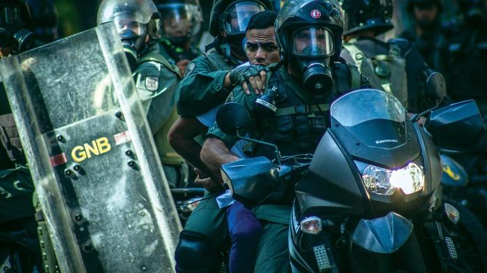 Members of the National Bolivarian Police detain a demonstrator at anti-government protests in Caracas, Venezuela, March 22, 2014.