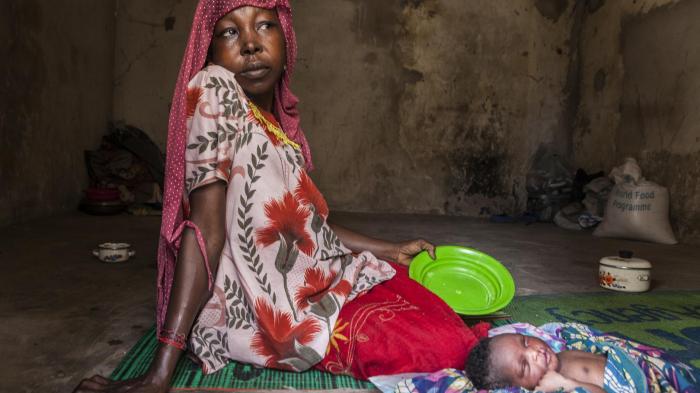 After returning from Cameroon, a Nigerian woman sits with her new-born in the militarized displaced persons camp in Banki, northeast Nigeria, where a Boko Haram attack in early September killed 18 civilians.