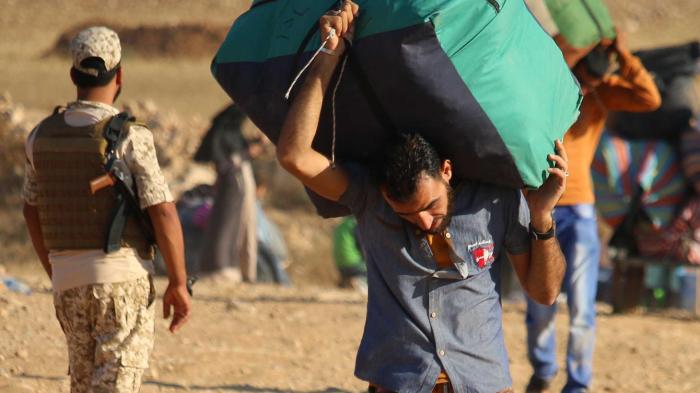 Syrian refugees carry belongings as they return to Syria after crossing the Jordanian border near the town of Nasib, in the southern province of Daraa, on August 29, 2017. 