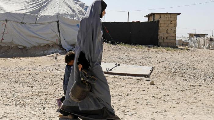 A woman walks with a child in Roj camp, which holds foreign wives and children of Islamic State (ISIS) members, in northeast Syria, September 2018. © 2018 Delil Souleiman/AFP/Getty Images