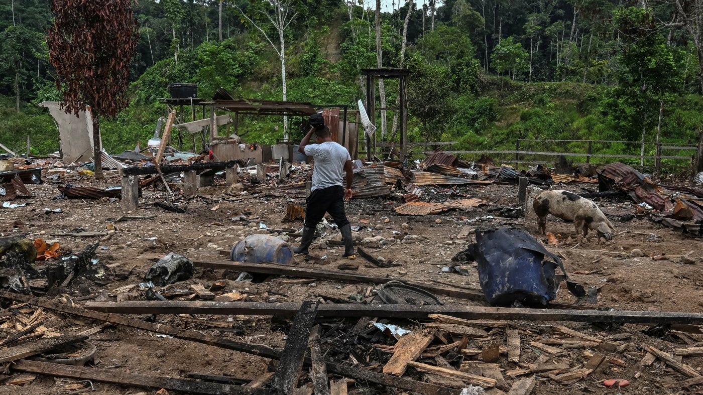 A farmer walks amidst rubble