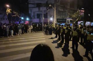 Chinese police officers block off access to a site where protesters had gathered in Shanghai on November 27, 2022.