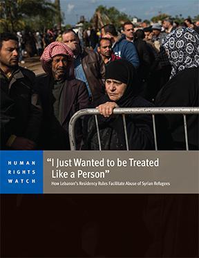 Syrian refugees line up to register or renew their registration at the UNHCR compound in Tripoli, in North Lebanon. A woman stands by a barrier.
