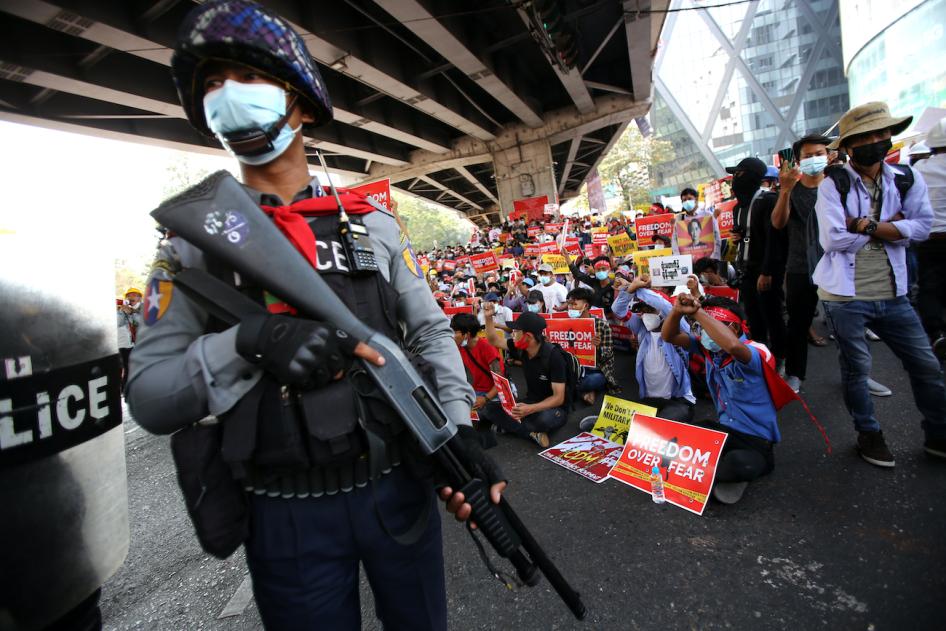 Un policier avec le doigt sur la gâchette de son fusil, photographié devant des manifestants protestant contre le coup d'État à Yangon, au Myanmar, le 19 février 2021. 