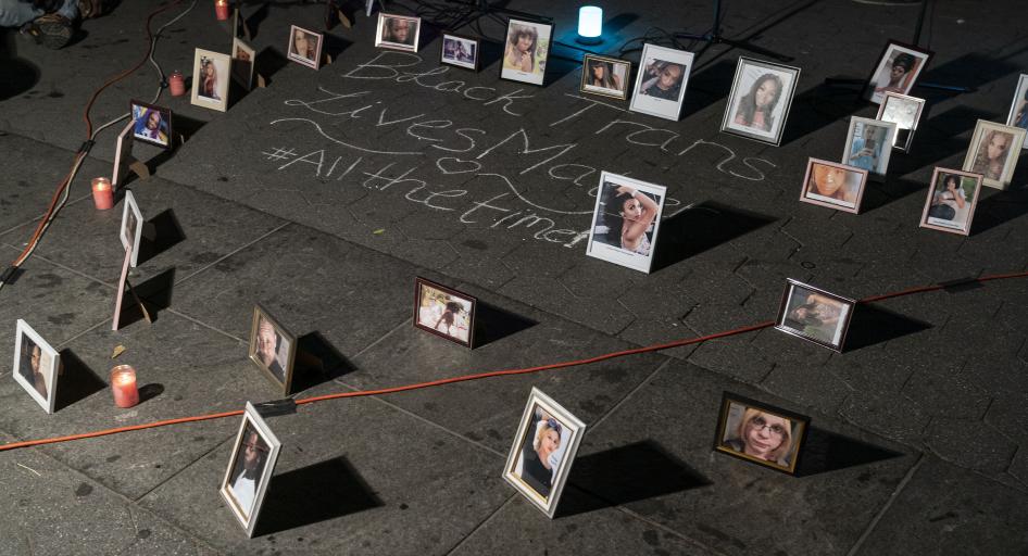 Framed photos placed on the ground around chalk writing that says "Black trans lives matter #allthetime"