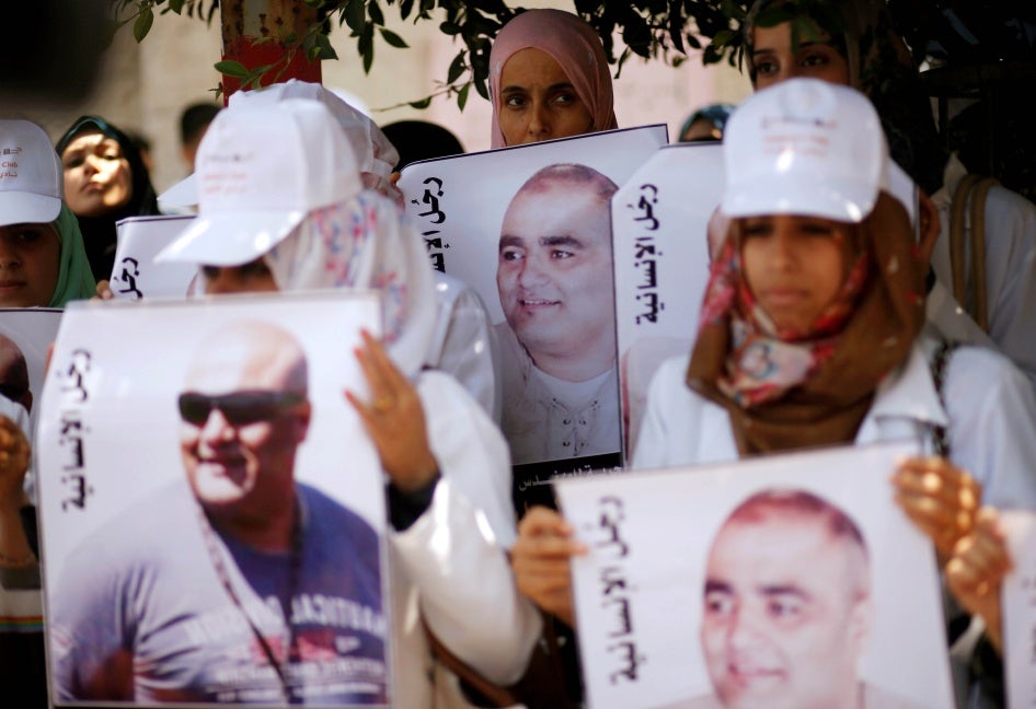 متظاهرون فلسطينيون يحملون صور محمد الحلبي، وهو موظف إغاثة في غزة تحتجزه إسرائيل منذ يونيو/حزيران 2016 بدون إدانته بجريمة، خلال مظاهرة تضامن مع الحلبي، مدينة غزة، 7 أغسطس/آب 2016.  