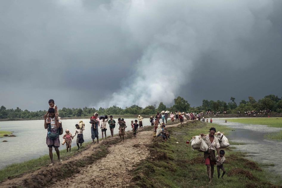 Refugees walk next to a river
