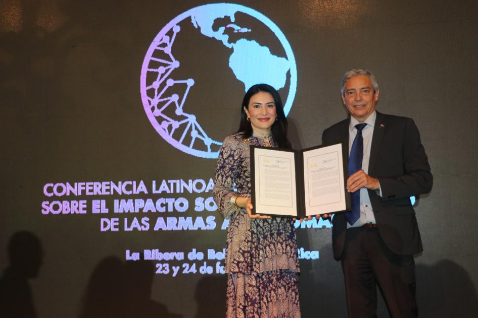 Two people pose together holding a document
