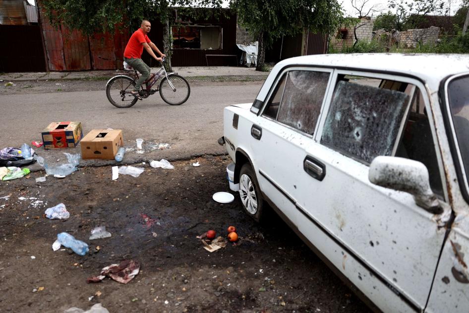 Un homme passe à vélo devant l'endroit où une femme a été tuée par une frappe d'arme à sous-munitions russe à Lyman, dans la région de Donetsk en Ukraine, le 8 juillet 2023. 