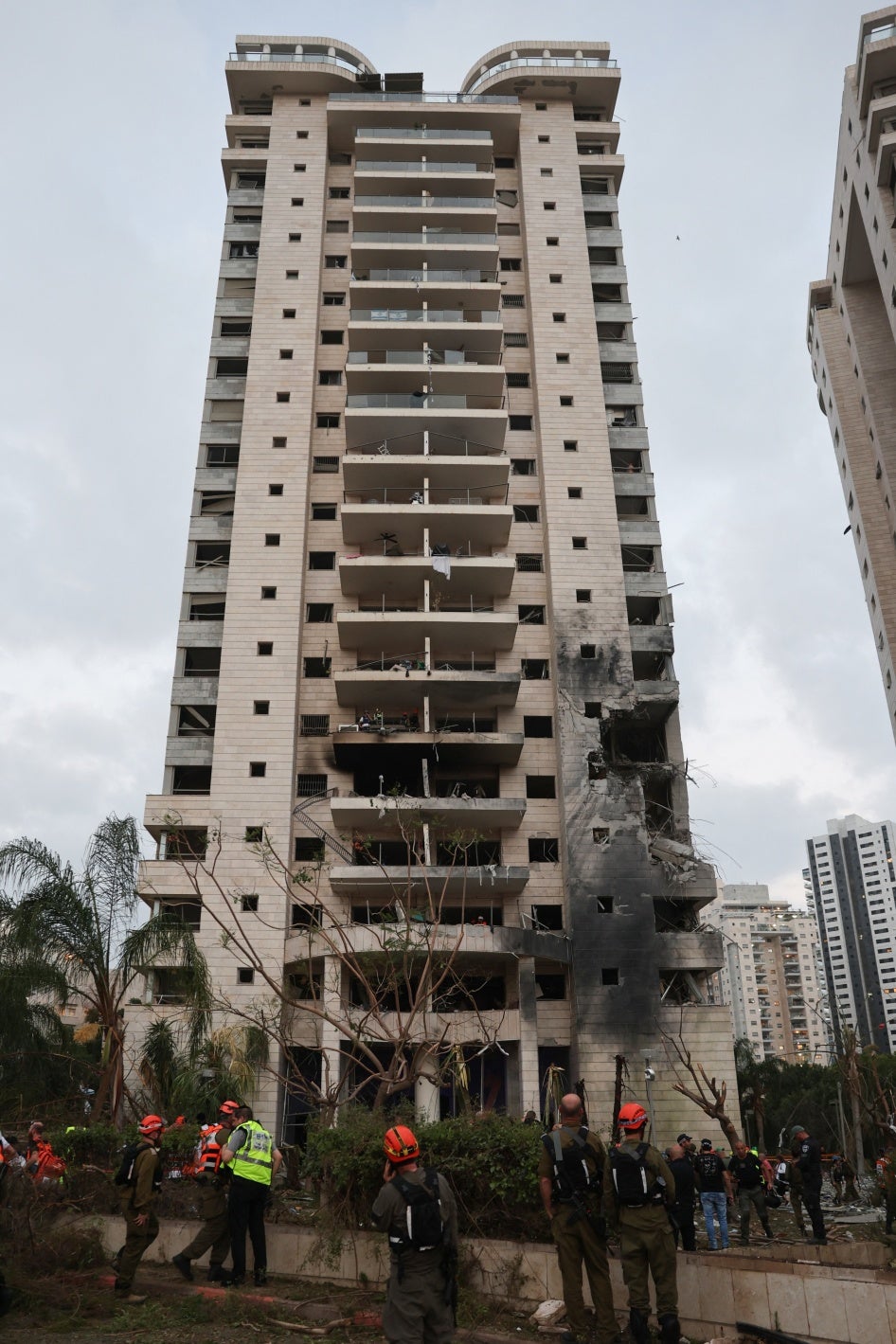 כיתוב: צוותי חירום והצלה בסמוך לבניין שניזוק מפגיעת טיל בליסטי איראני בפתח תקווה ב-16 ביוני 2025