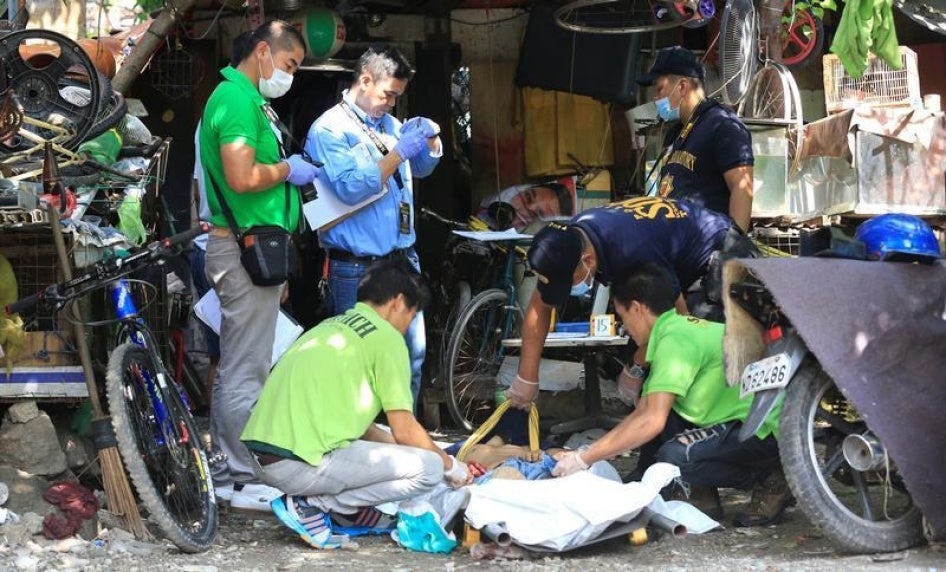 Members of the Philippine National Police (PNP) investigation unit checks the body of one of the five suspected drug pushers killed in a police operation in Quiapo city, metro Manila, Philippines July 3, 2016. 