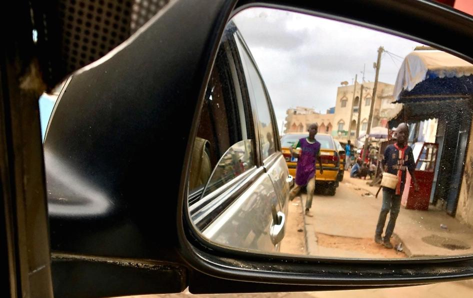 Deux enfants talibés, aperçus dans un rétroviseur, mendient auprès d’automobilistes dans les rues de Dakar, au Sénégal, le 21 juin 2018.  