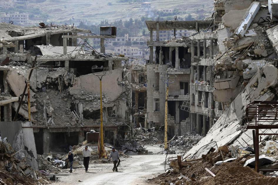 Deux hommes et un garçon marchent parmi les décombres d’immeubles bombardés dans la ville de Zabadani, située près de Damas, en Syrie, le 18 mai 2017.