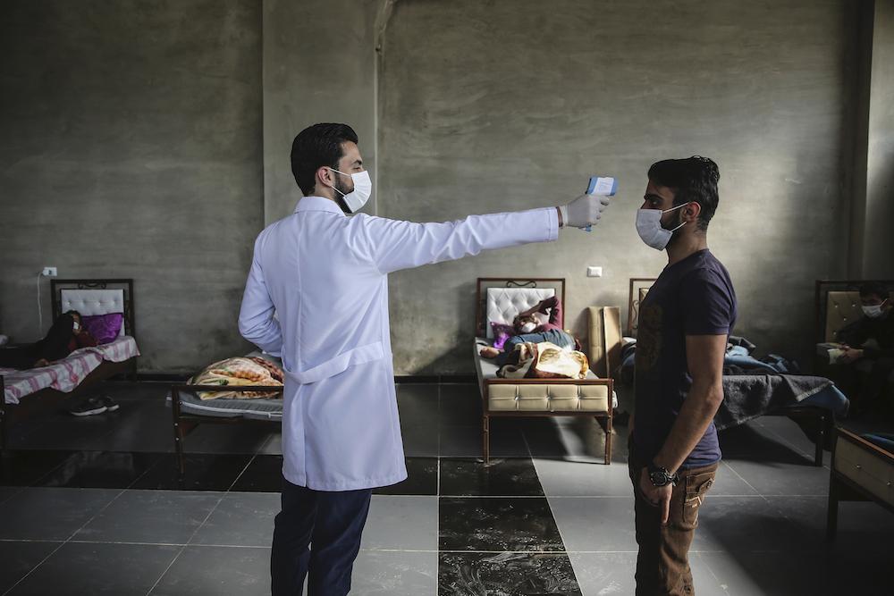 A healthcare worker checks a man's temperature using a thermometer