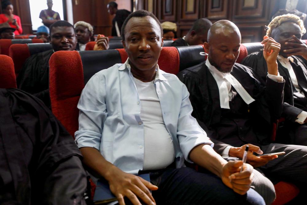 A man sits in a courtroom next to lawyers