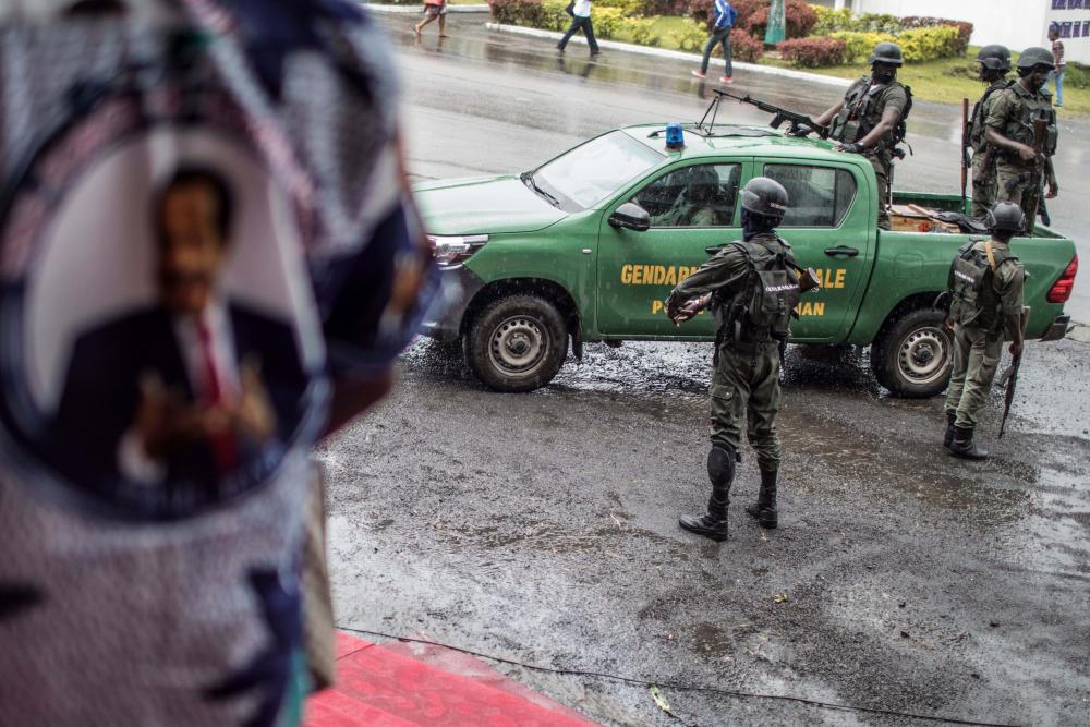 Uniformed officers stand near a police vehicle 