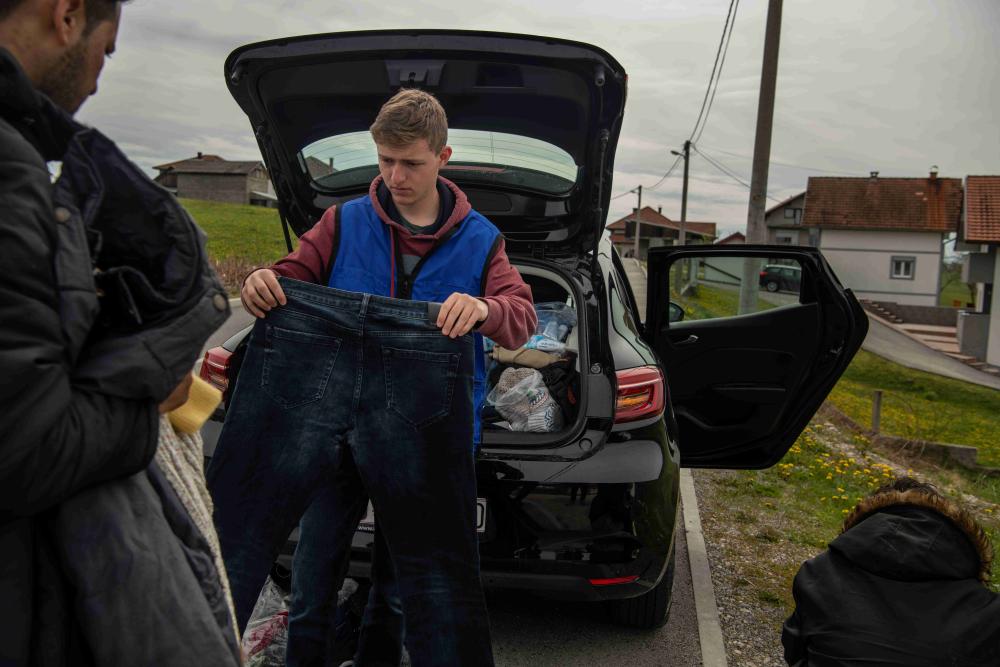 Klemens Danner, un voluntario que trabaja para el Servicio Jesuita a Refugiados en Bosnia-Herzegovina, distribuye ropa a un grupo de personas afganas que dijeron que policías croatas las habían expulsado temprano por la mañana sin permitirles solicitar asilo, abril de 2023. 