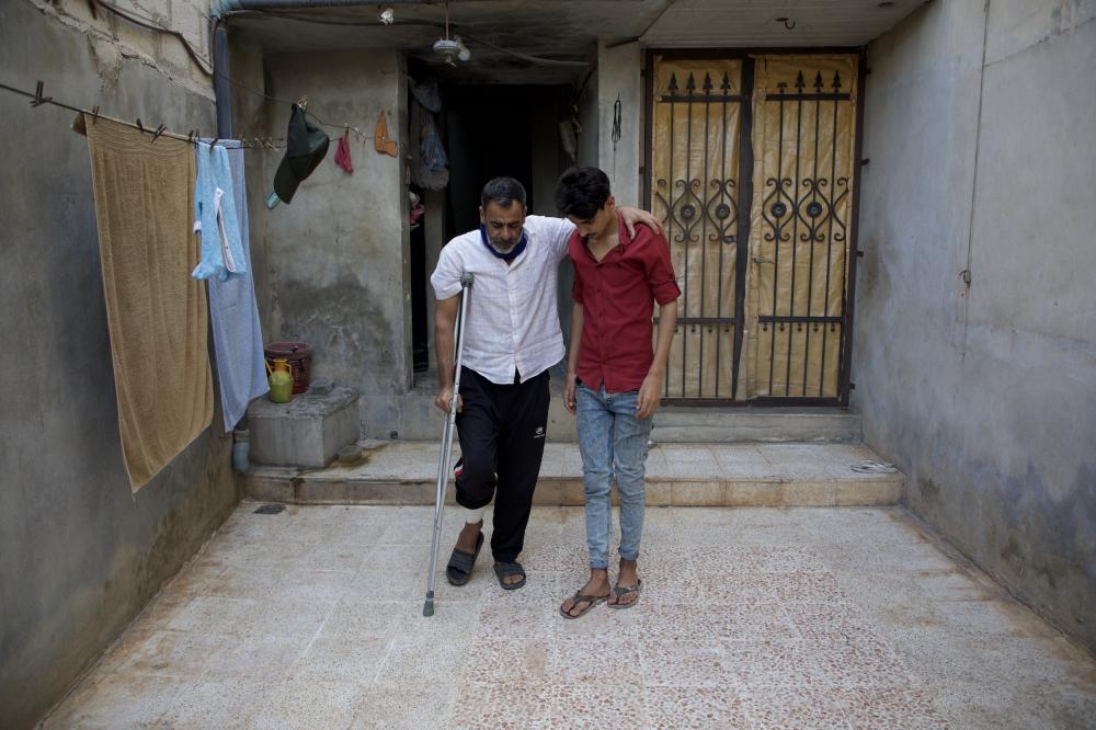 Abdel Karim Bastin, 49, injured in the bombardment of the village Termanin on October 6, leans on his son in front of their home, Syria, October 14, 2023. Bastin lost his nephew in the attack.