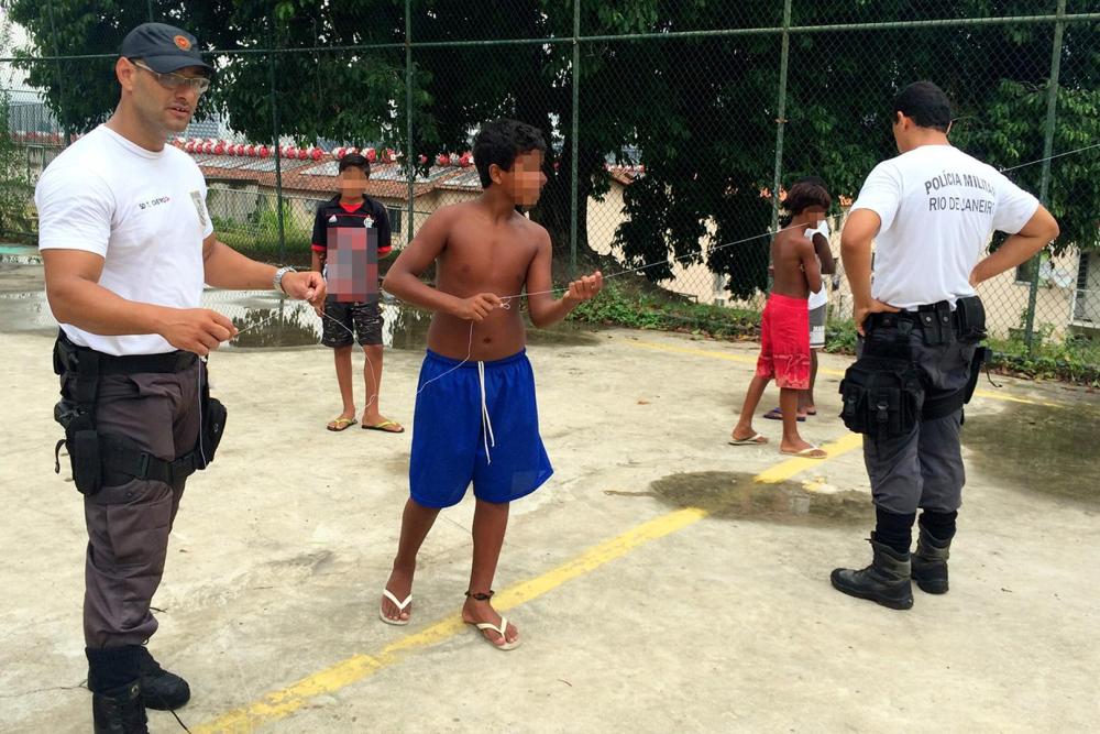 Military police officers Thiago Castro (l) and Wallace Justo (r) play with children at the Mangueira favela on January 14, 2016.© 2016 César Muñoz Acebes/Human Rights Watch 