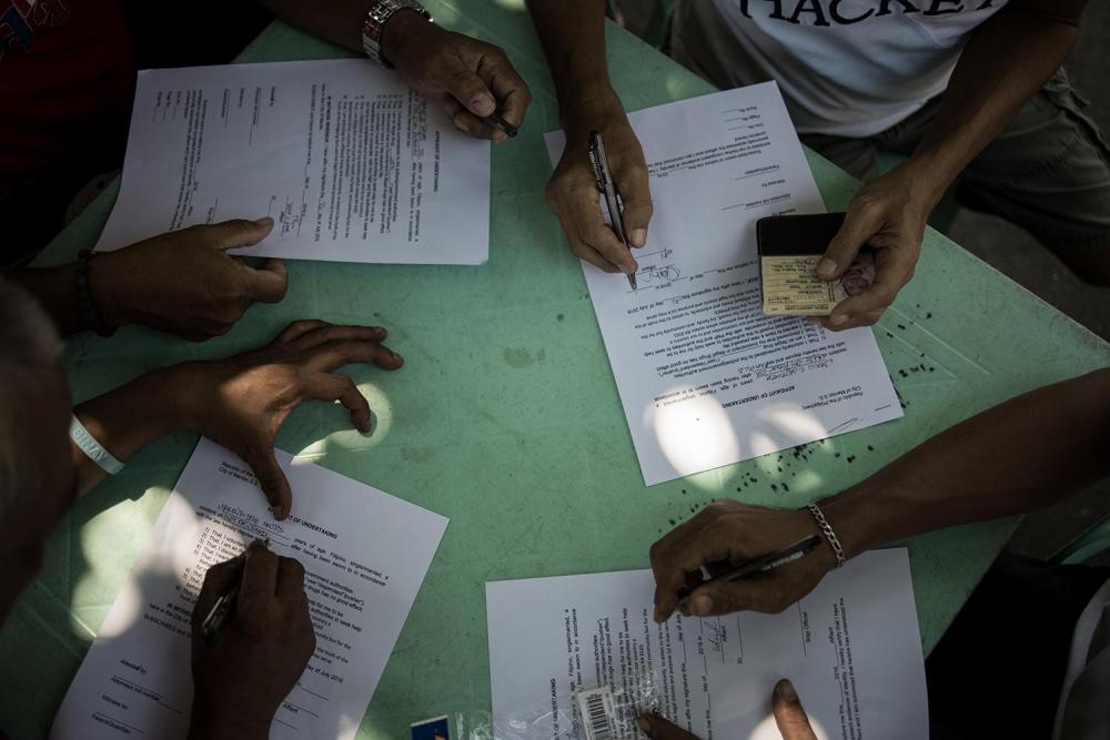 People who voluntarily surrendered during Operation Double Barrel Tokhang sign an affidavit admitting that they've used drugs and that they will cooperate with the authorities in their anti-drug campaign, July 27, 2016.