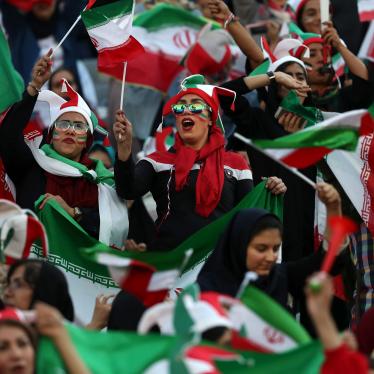 Women cheer holding flags and wearing face paint