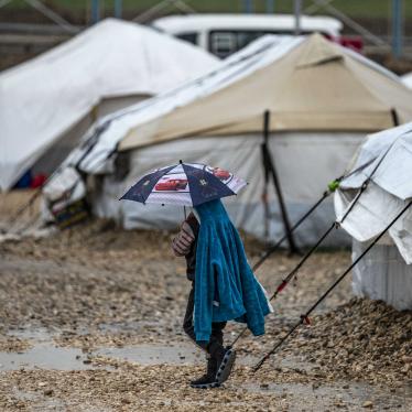 A young person holds an umbrella as he walks in the rain at Camp Roj, where relatives of people suspected of belonging to the Islamic State (IS) group are held, in Syria's northeastern Hasakah province, on March 4, 2021. 