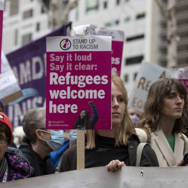 Protesters hold placards reading "refugees welcome here" at a demonstration