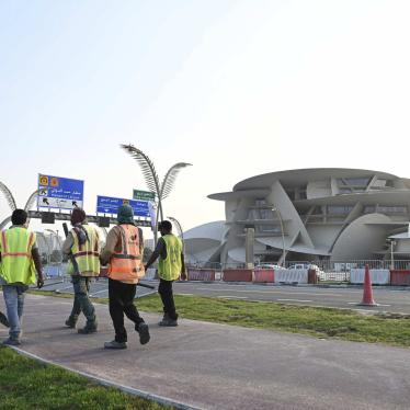 Construction workers walking by the National Museum of Qatar. 