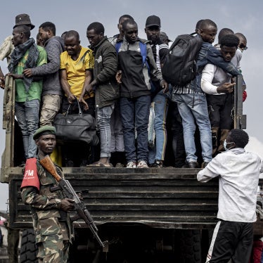 M23 fighters stand guard as people board a truck