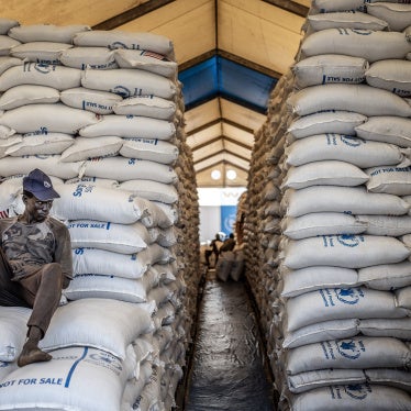 A worker sits atop sacks of food aid in a hangar where supplies are piling up because deliveries have halted because of the conflict at a World Food Programme (WFP) warehouse in Bor, Jonglei State, on February 13, 2026.