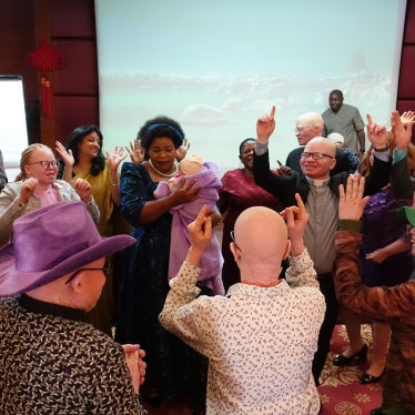 During the June 12 launch of the joint report by Human Rights Watch and African Albinism Network on discrimination against people with albinism in employment, Malawi’s Minister of Gender, Children, Disability and Social Welfare dances with a young child with albinism as community members gather around them on the eve of International Albinism Awareness Day in Lilongwe. 