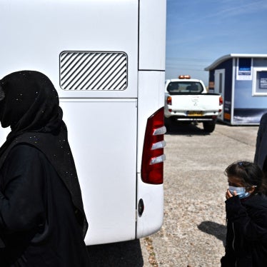 Migrants walk towards a bus to be taken for processing after disembarking from a Royal National Lifeboat Institution (RNLI) lifeboat on a beach after crossing the English Channel, in Dungeness, England, on June 15, 2022.